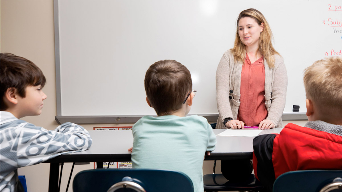 Photo of student-teacher interacting with a young children in a classroom.