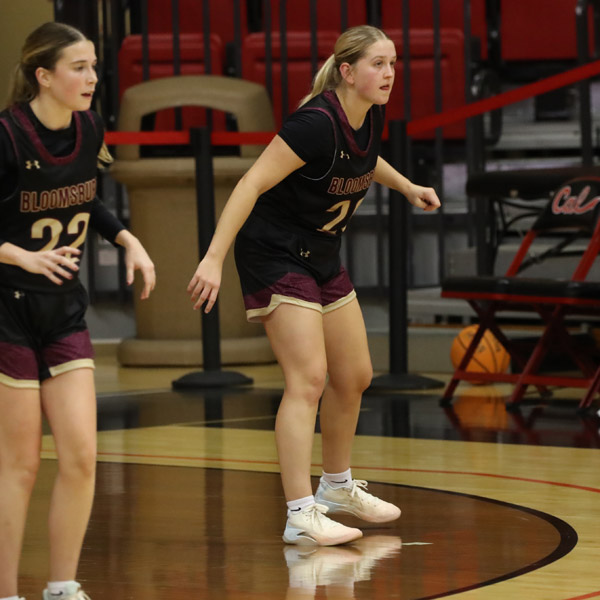 Lauren Kirsch and a  teammate watch the action on the basketball court.