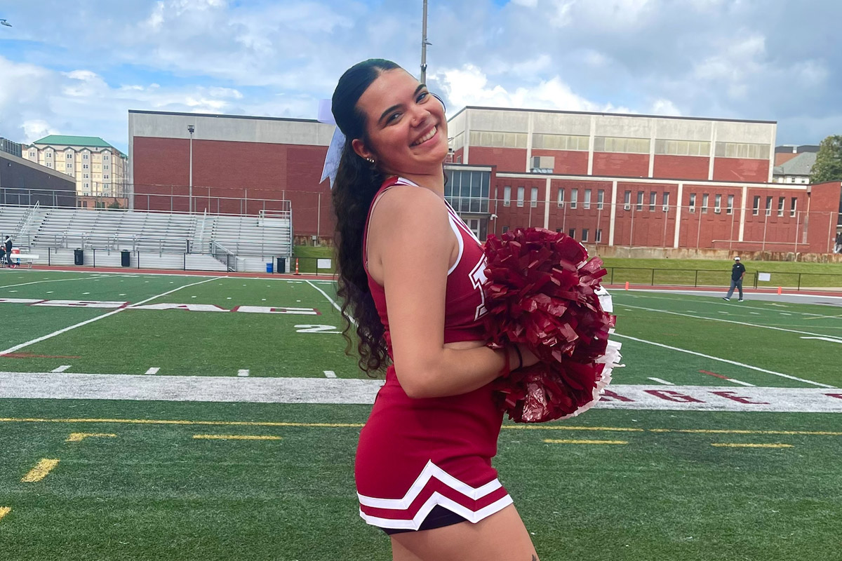 Mackenzie Vajda in her cheerleading uniform on the football field at IUP.
